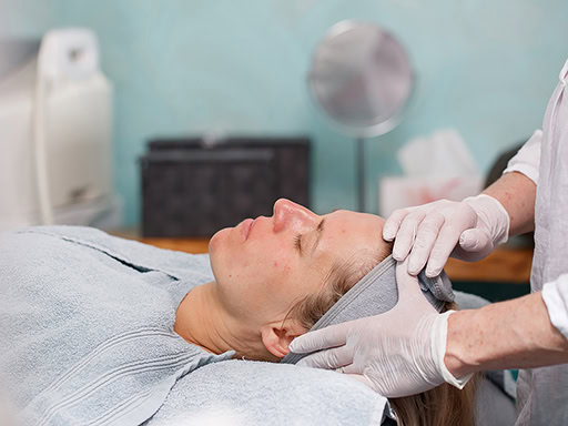 Hautpflegebehandlung bei einer Kosmetikerin mit Gesichtsmassage in einem Behandlungsraum.