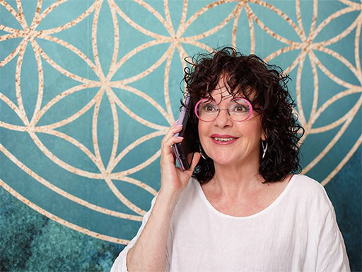 Naturkosmetikerin spricht am Telefon vor bunter geometrischer Wanddekoration.